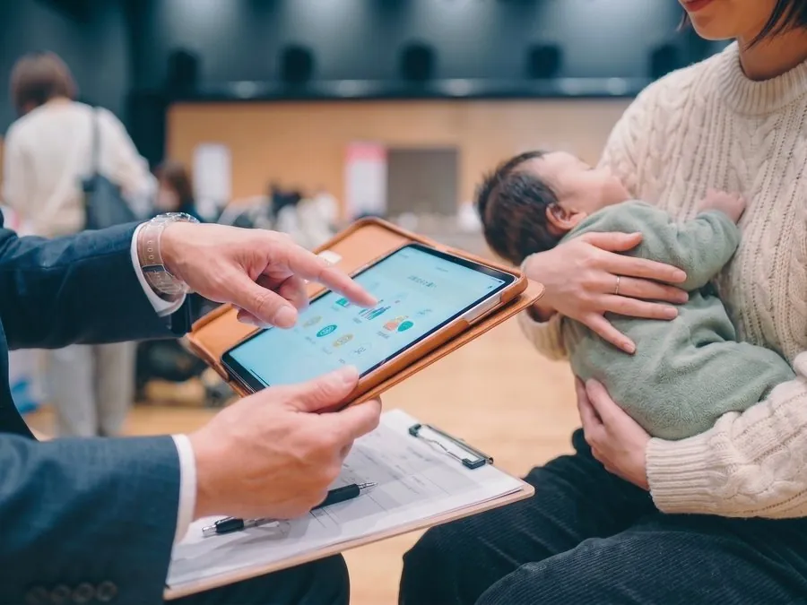 タブレットで資料を見せながら話すスタッフと来場者
